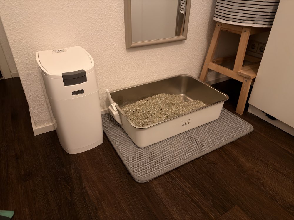 Katzenklo auf einer Matte, links daneben der weiße LittyCat-Eimer